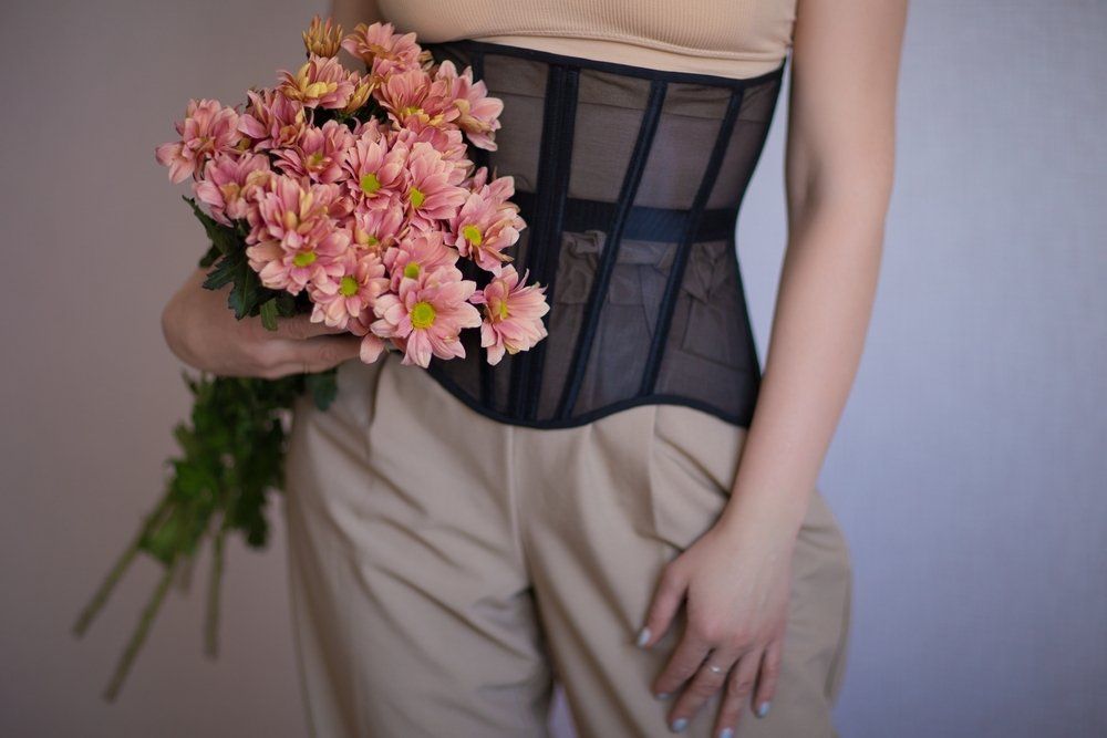 Girl in a Beige Top, Corset and Trousers and Holding Flowers — Shona's Lingerie in Hermit Park, QLD