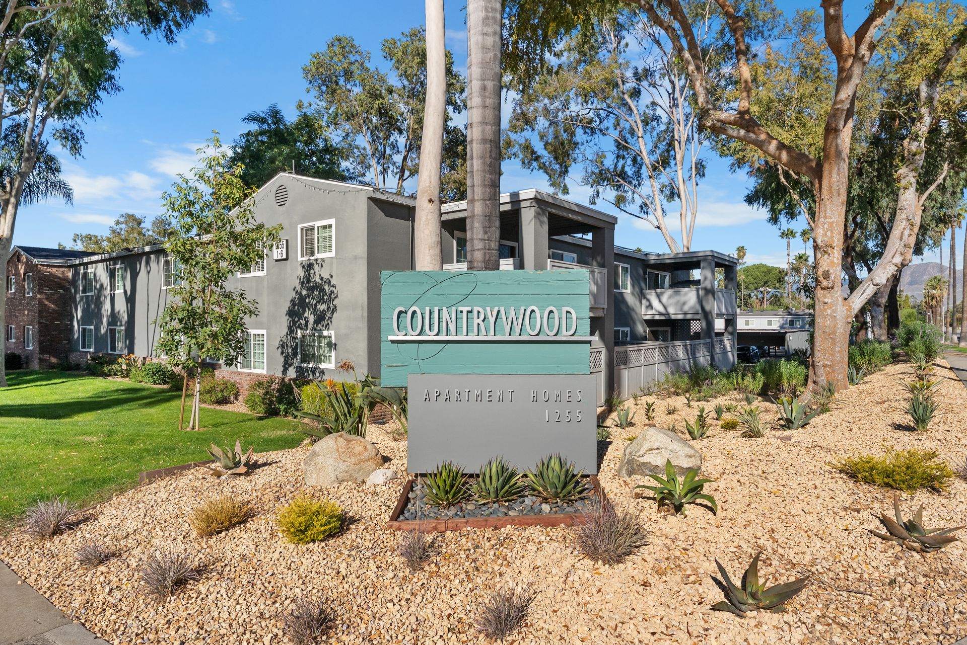 Front Monument apartment sign surrounded by rocks and desert plants