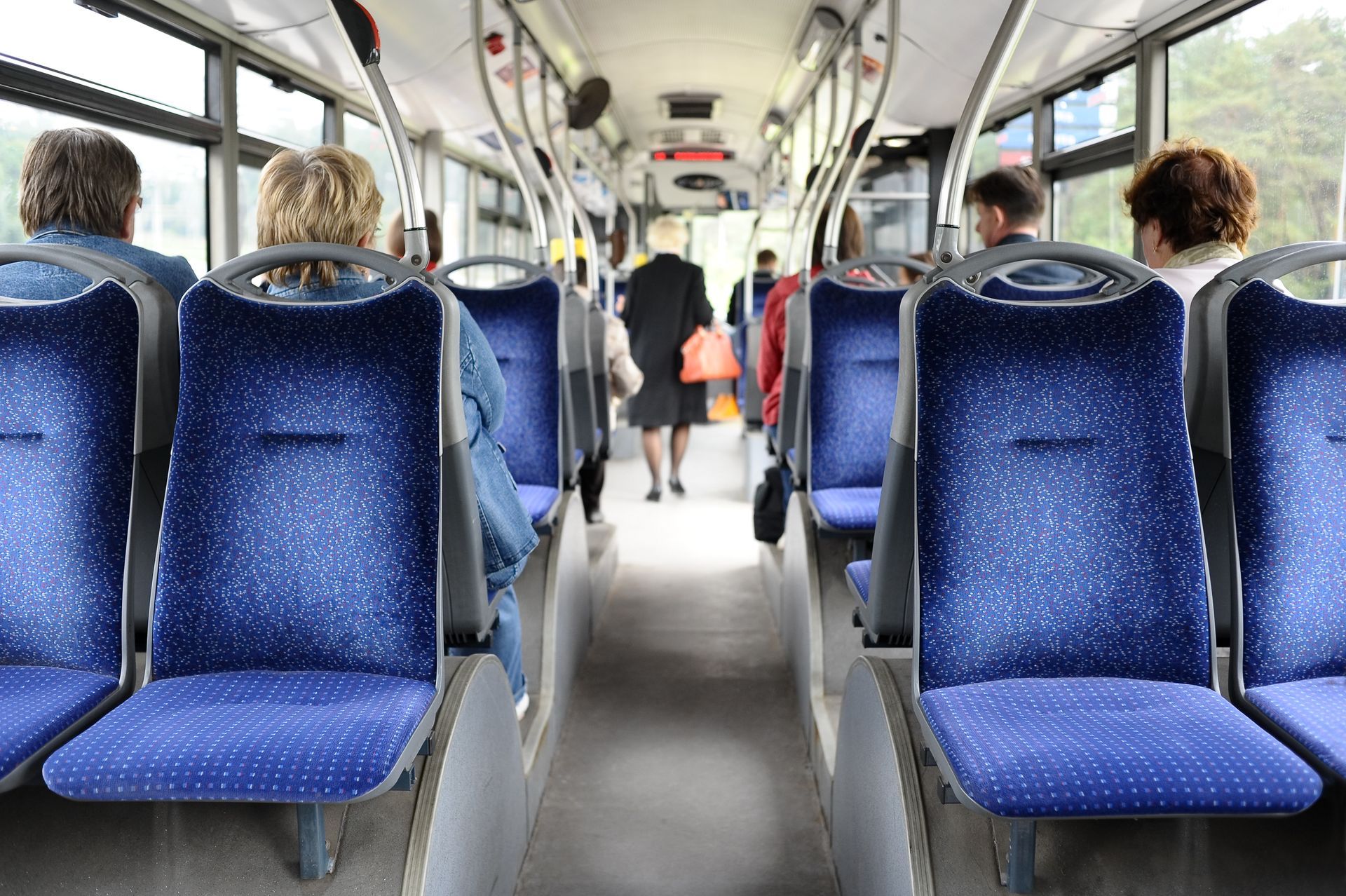 a group of people are sitting on a bus with blue seats .
