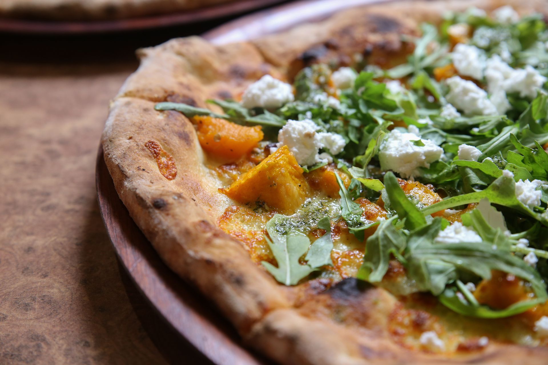 a close up of a pizza on a wooden plate on a table .
