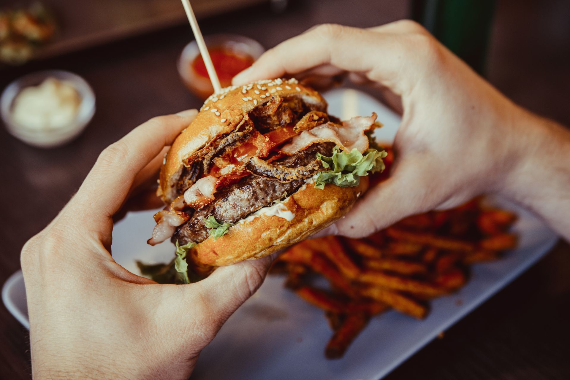 a person is eating a hamburger and french fries at a restaurant .