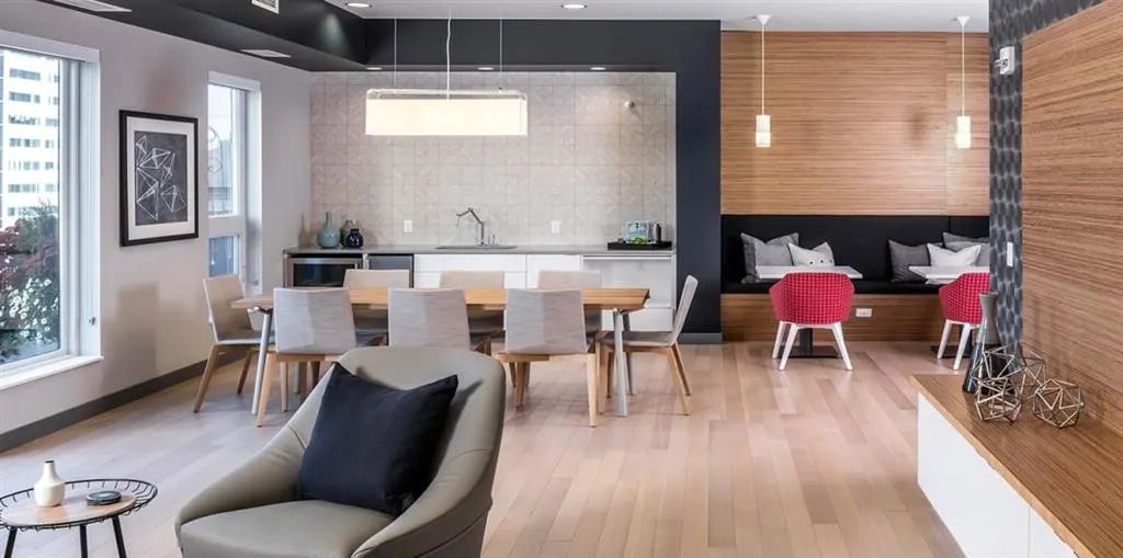 Modern living space with light wood flooring, dining table, kitchen, seating area.