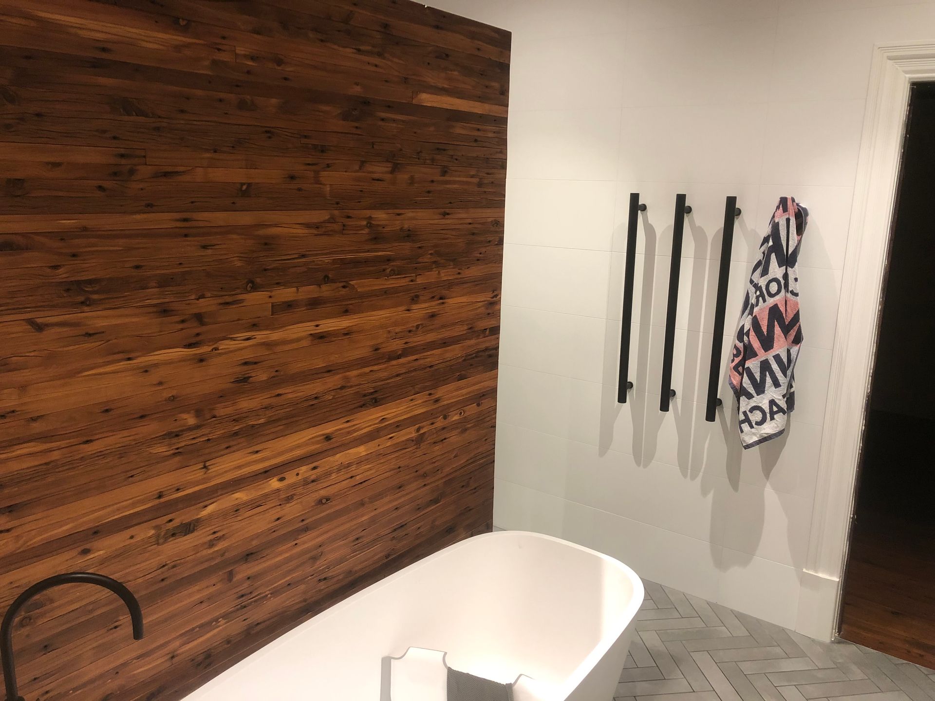 A bathroom with a bathtub and a wooden wall.