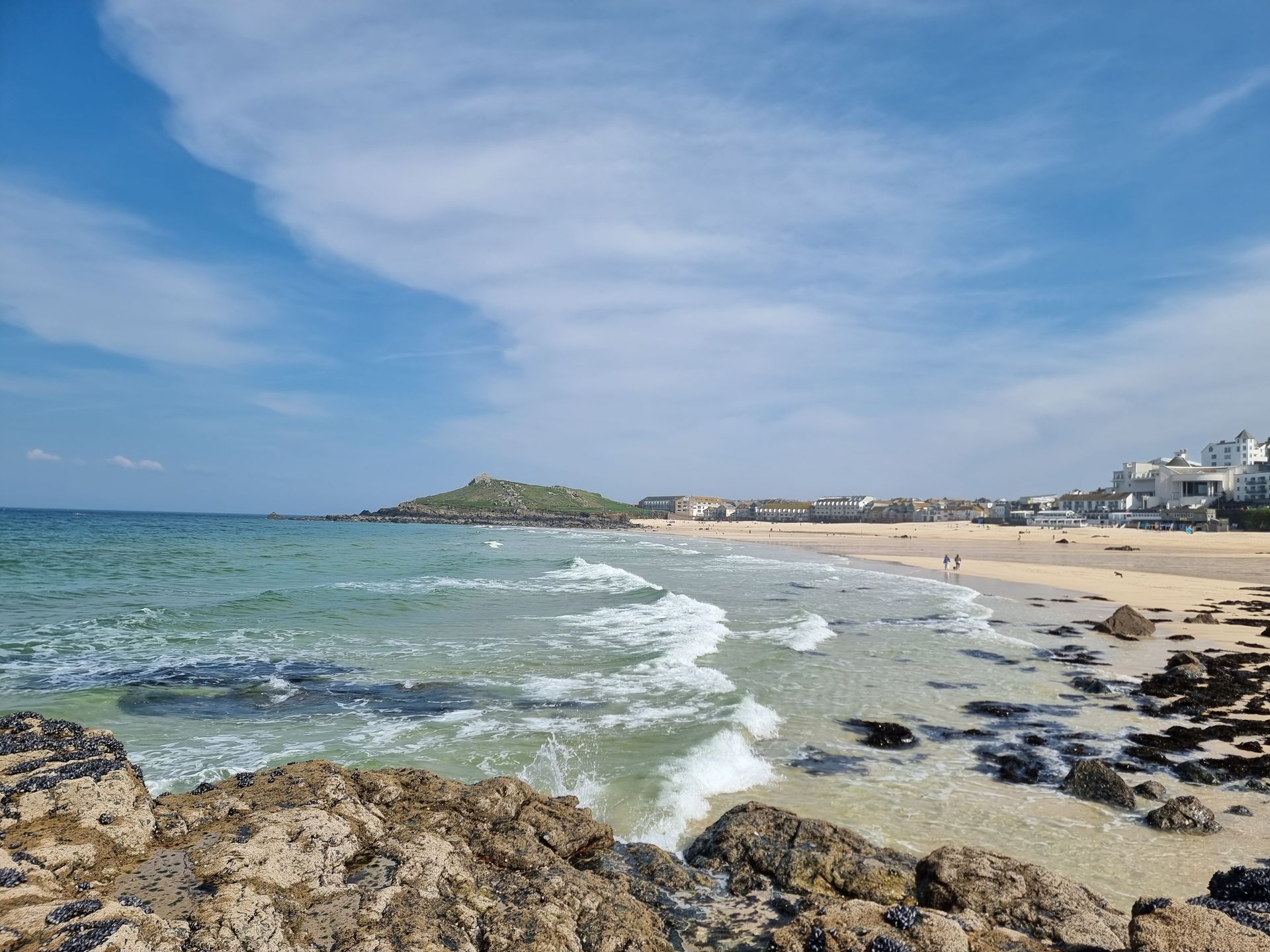 A beach with waves crashing against the rocks on a sunny day.