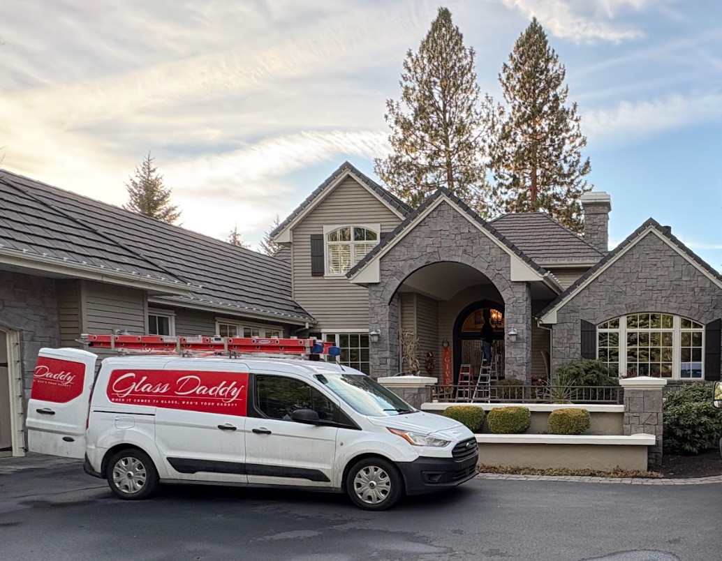 White service van parked outside a stone-and-wood house with an arched entryway