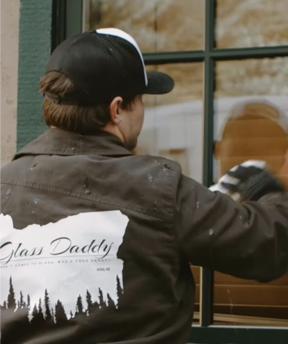 A man wearing a hat and a jacket that says glass daddy