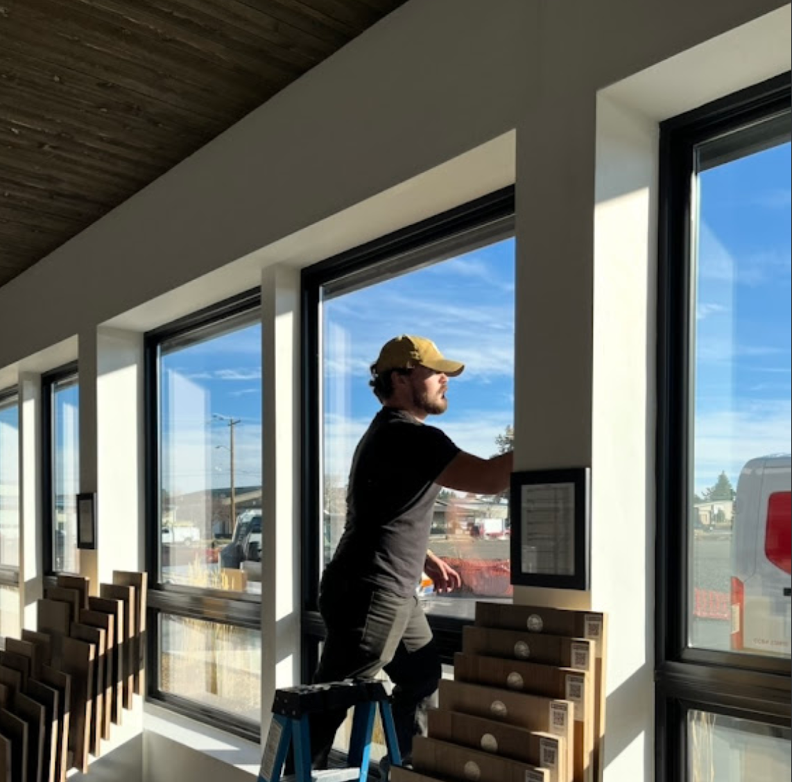 A man standing on a ladder looking out a window