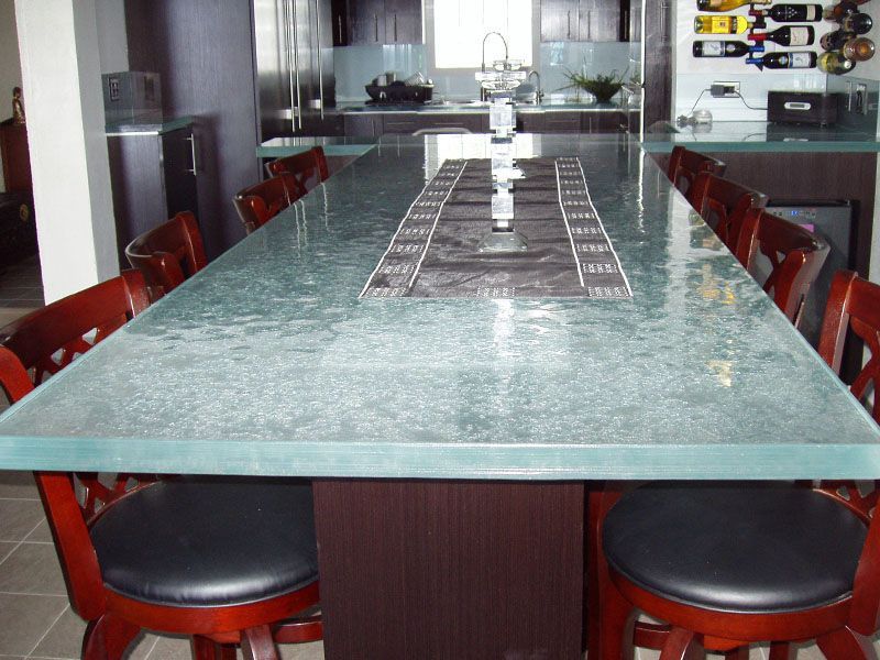 A kitchen with a long glass table and chairs