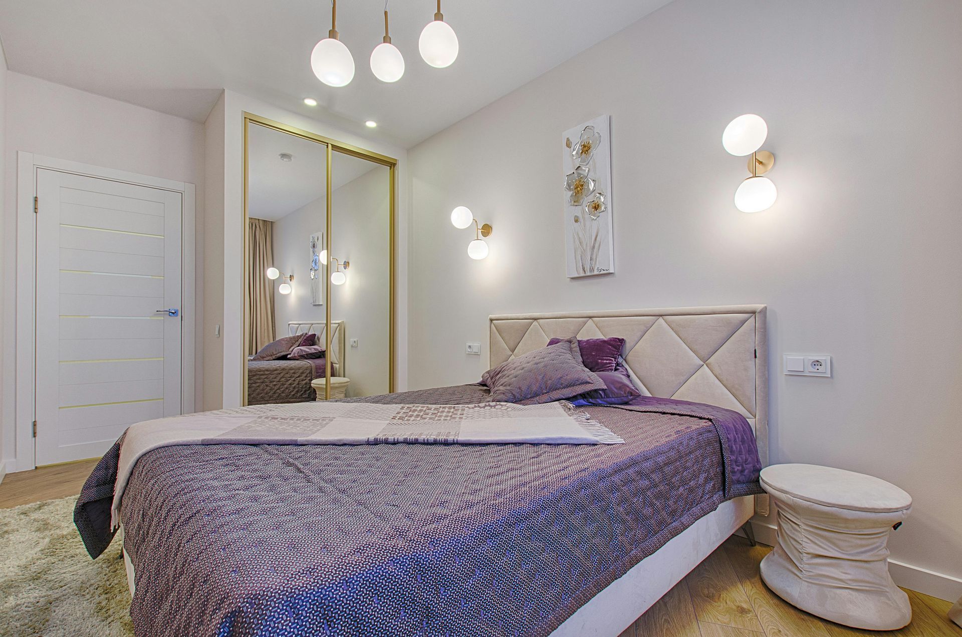 A bedroom with a bed , nightstand , mirror and sliding wardrobe.
