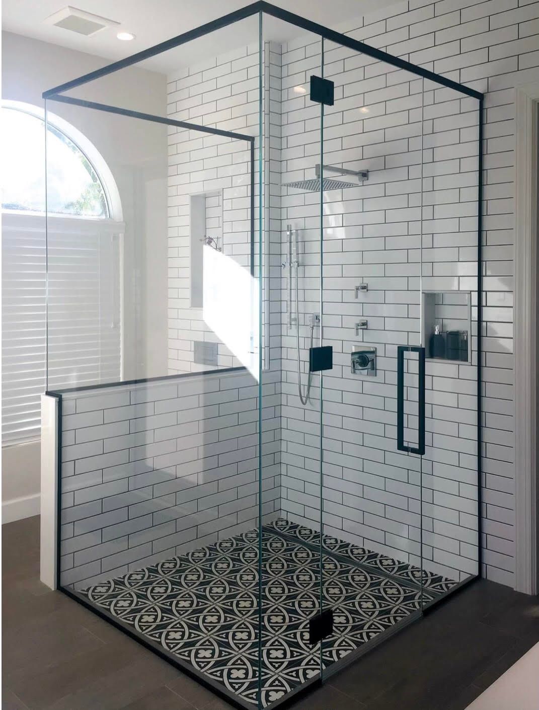 A shower stall with a black frame and white tiles