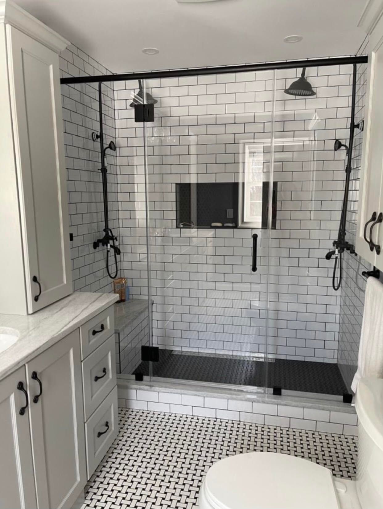 A bathroom with white brick walls , a toilet , sink and shower.