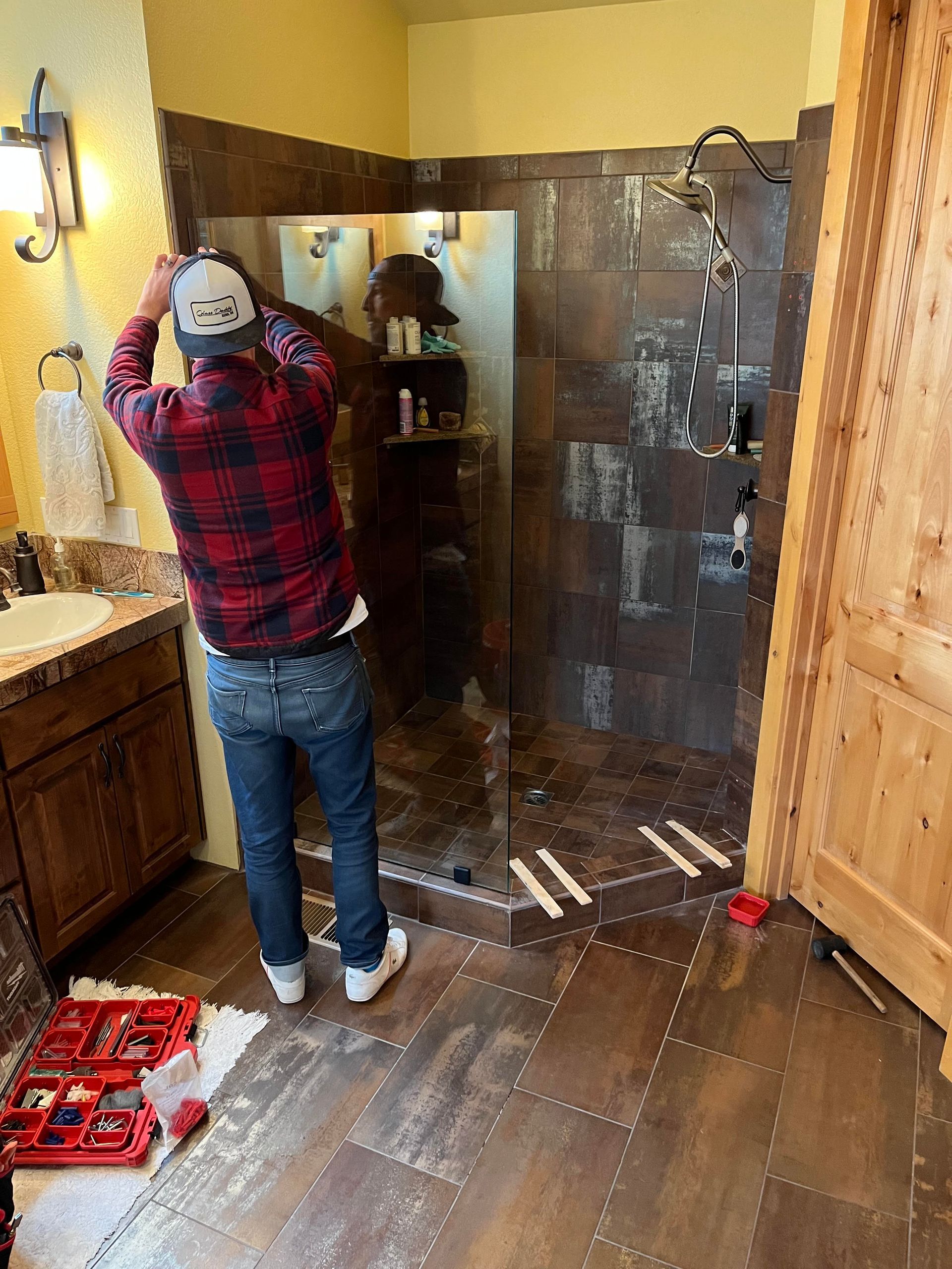 A man is installing a shower door in a bathroom.