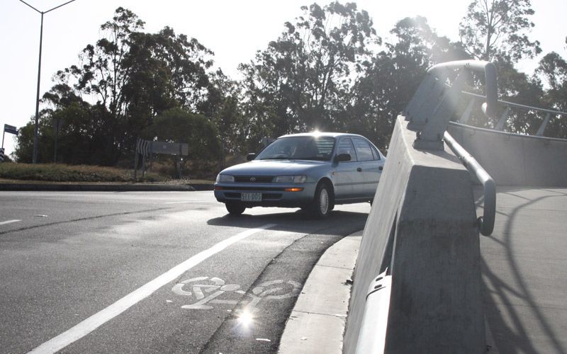 A car is driving down a road next to a bike lane