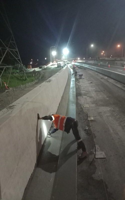 A man is crawling on the side of a highway at night.