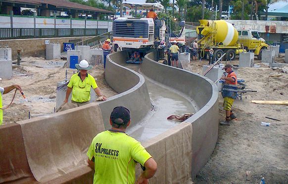 A group of construction workers are working on a concrete wall.