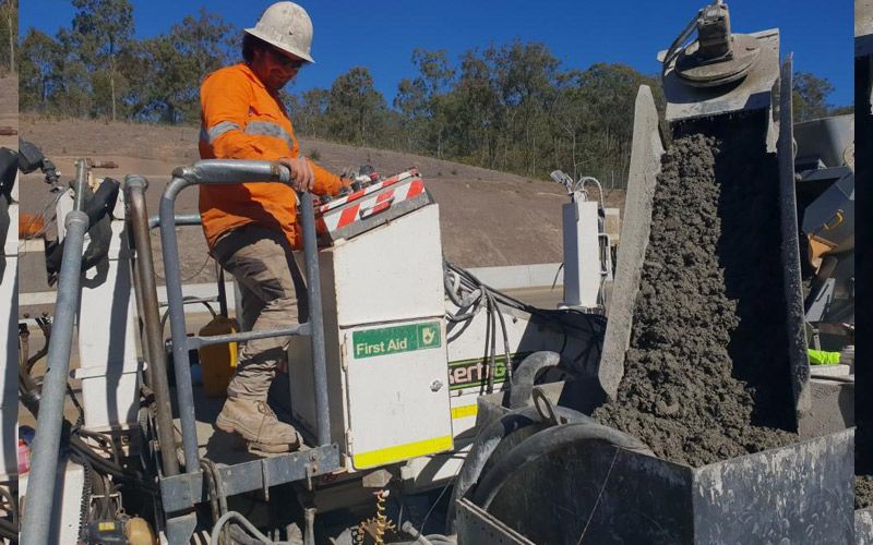 A man is sitting on a machine that is pouring concrete.