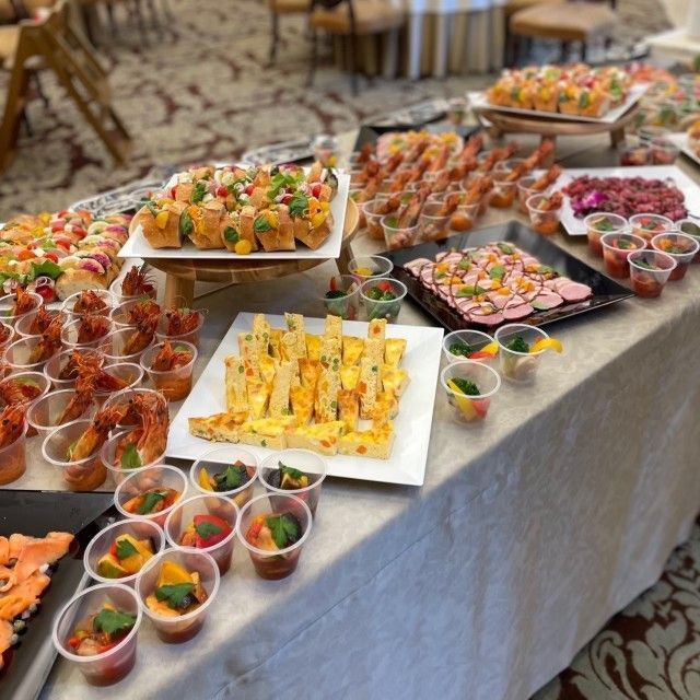 Buffet table with various appetizers: sushi, shrimp cocktails, and other small bites.