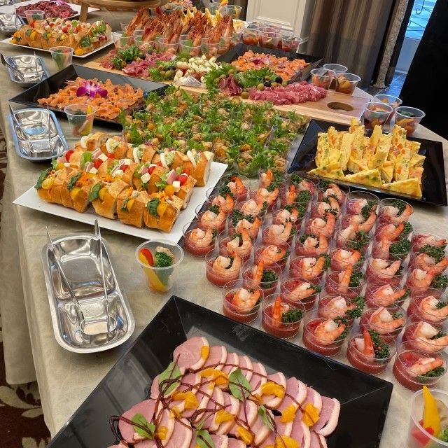 A buffet table laden with appetizers, including shrimp, sushi, and other bite-sized delicacies.