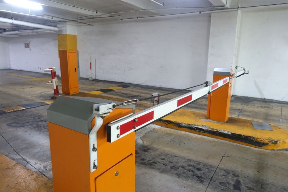 Orange parking barrier in a garage, arm raised. Yellow and gray details. — Strike Fencing & Gates In Tuggerah, NSW