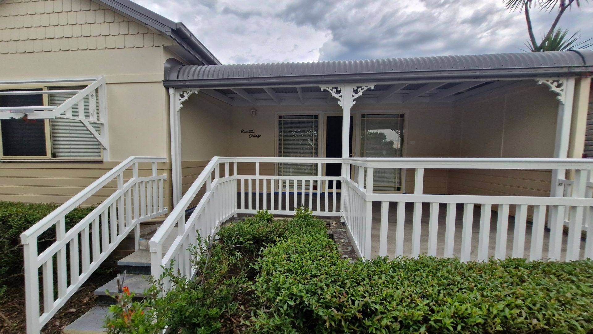 A House With a Front Porch, White Railings, and a Small Garden — Strike Fencing & Gates In Tuggerah, NSW