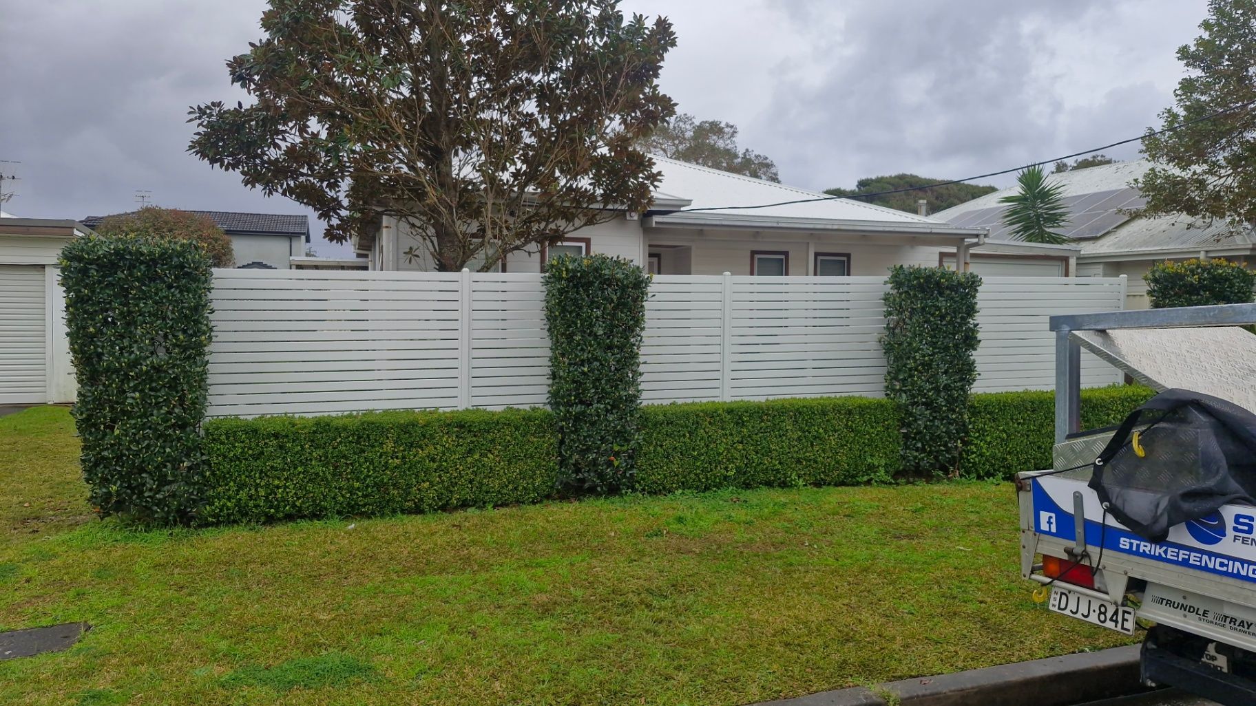 White Horizontal Slat Fence With Green Hedges and Topiary — Strike Fencing & Gates In Tuggerah, NSW