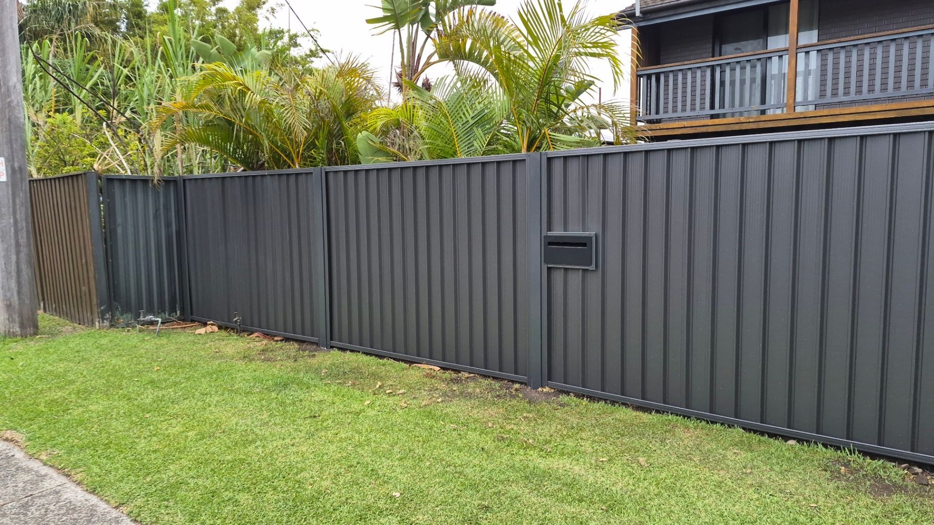 dark colourbound fence on the central coast with grass in front