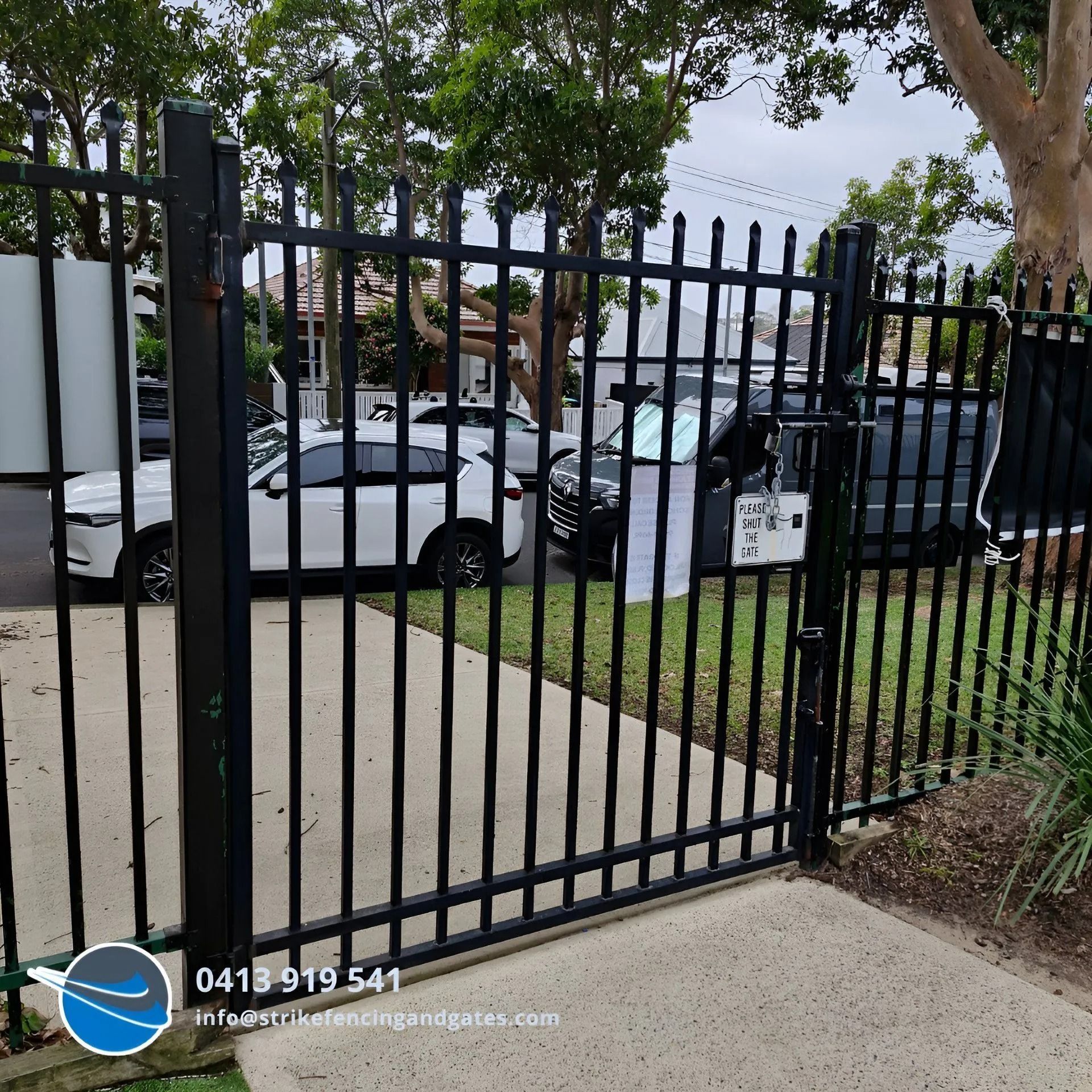 Black Metal Gate With Vertical Bars, Driveway, Cars Parked Behind the Gate — Strike Fencing & Gates In Tuggerah, NSW