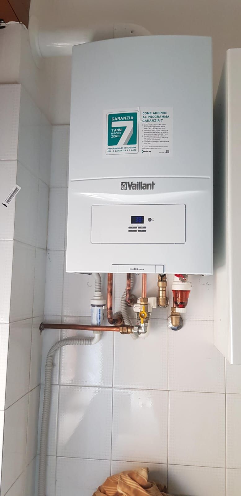 In un bagno c'è una caldaia bianca appesa al muro.