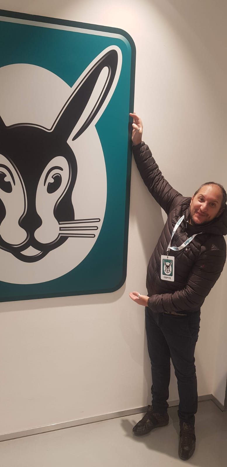 Un uomo è in piedi davanti al logo di un coniglio su un muro.