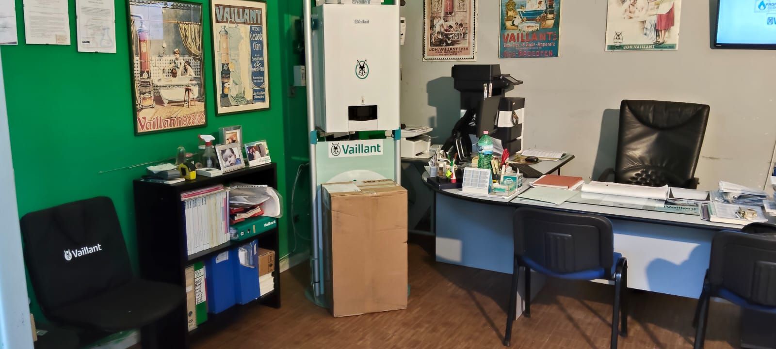 Una stanza con una scrivania, sedie, un computer e una parete verde.