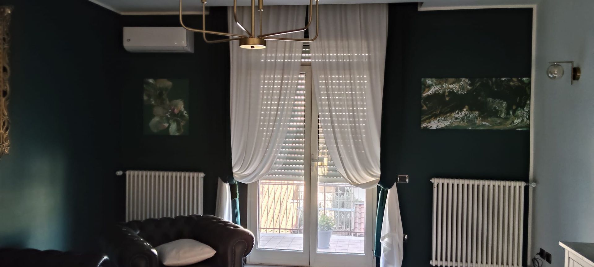 Un soggiorno con una sedia nera e tende bianche