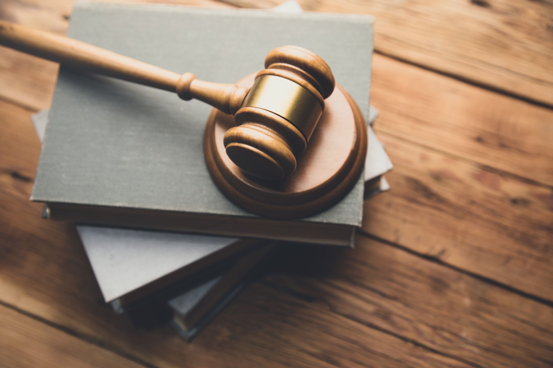 A wooden gavel resting on top of a stack of books on a wooden surface.