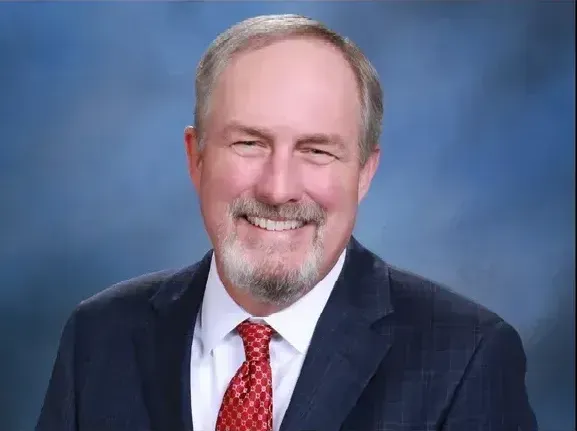 A man in a suit and tie is smiling for the camera.