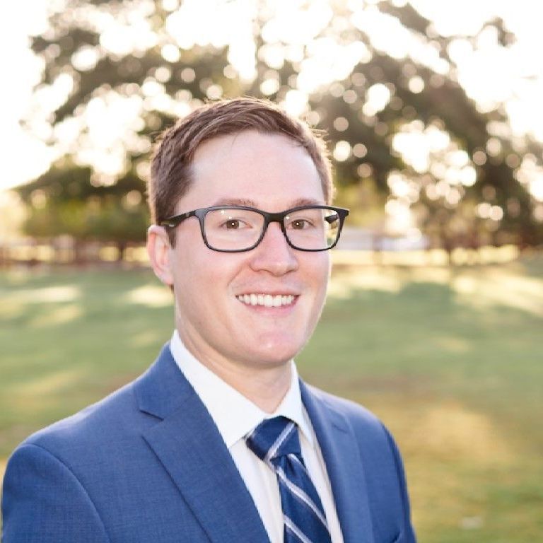 A man in a suit and tie is smiling for the camera