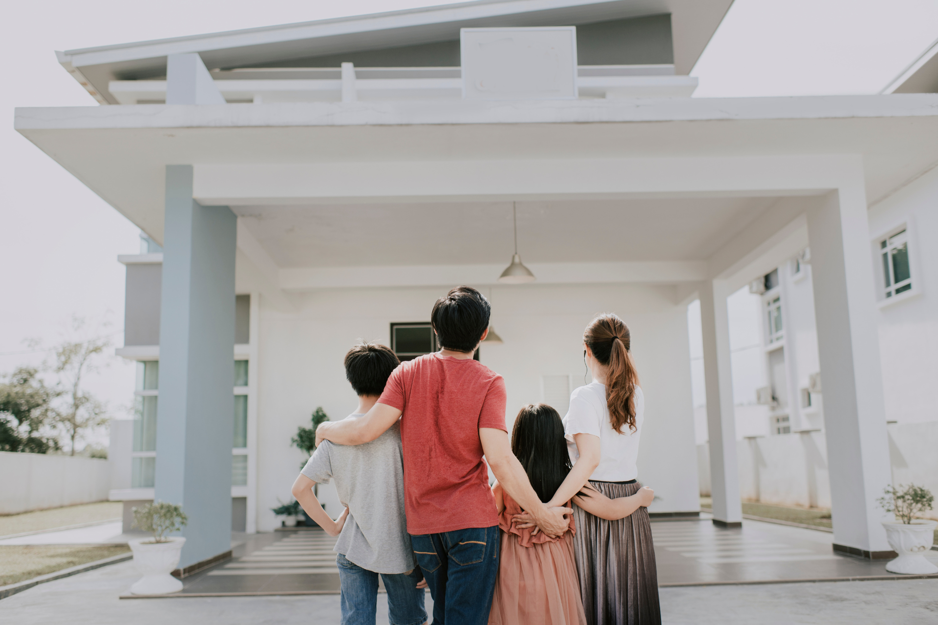 A family is standing in front of a house looking at it.