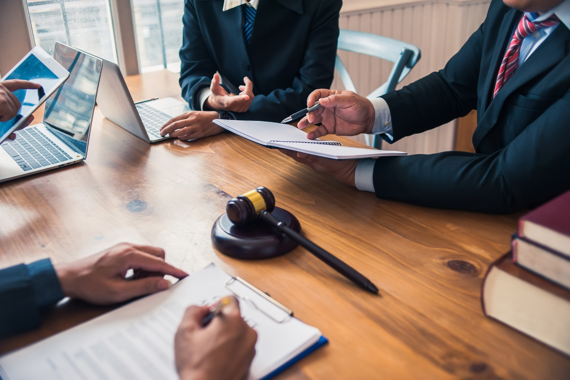 A group of lawyers are sitting around a wooden table.