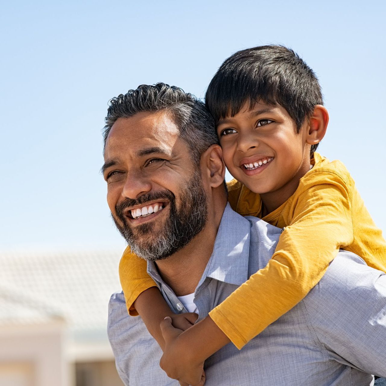 A man is carrying a little boy on his back.