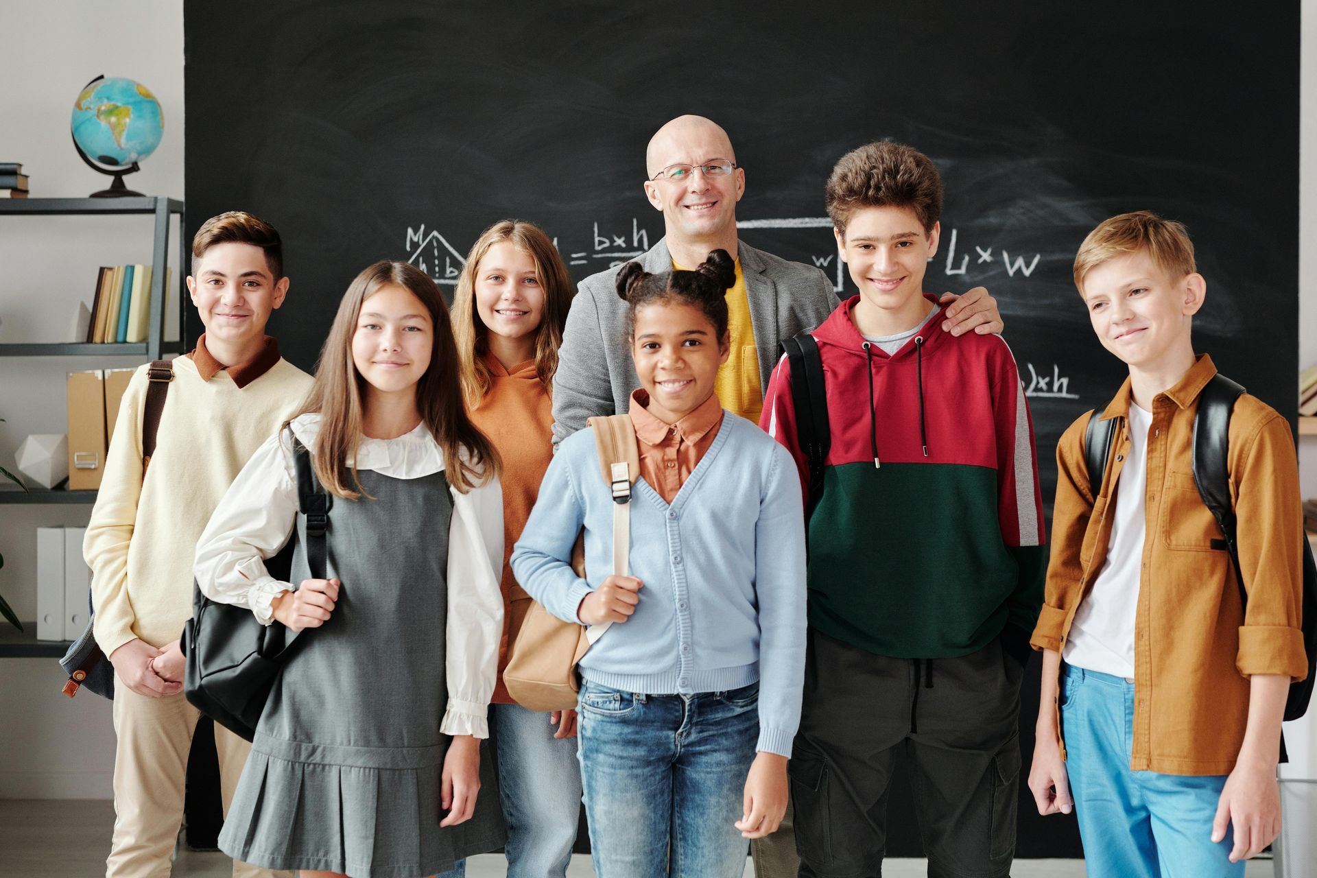 A group of children and their teacher are posing for a picture in a classroom.