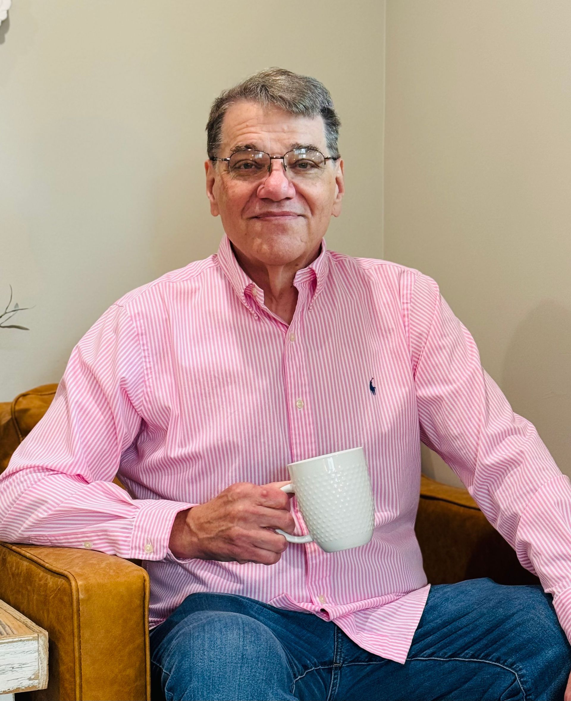 A man in a pink shirt is holding a coffee cup.