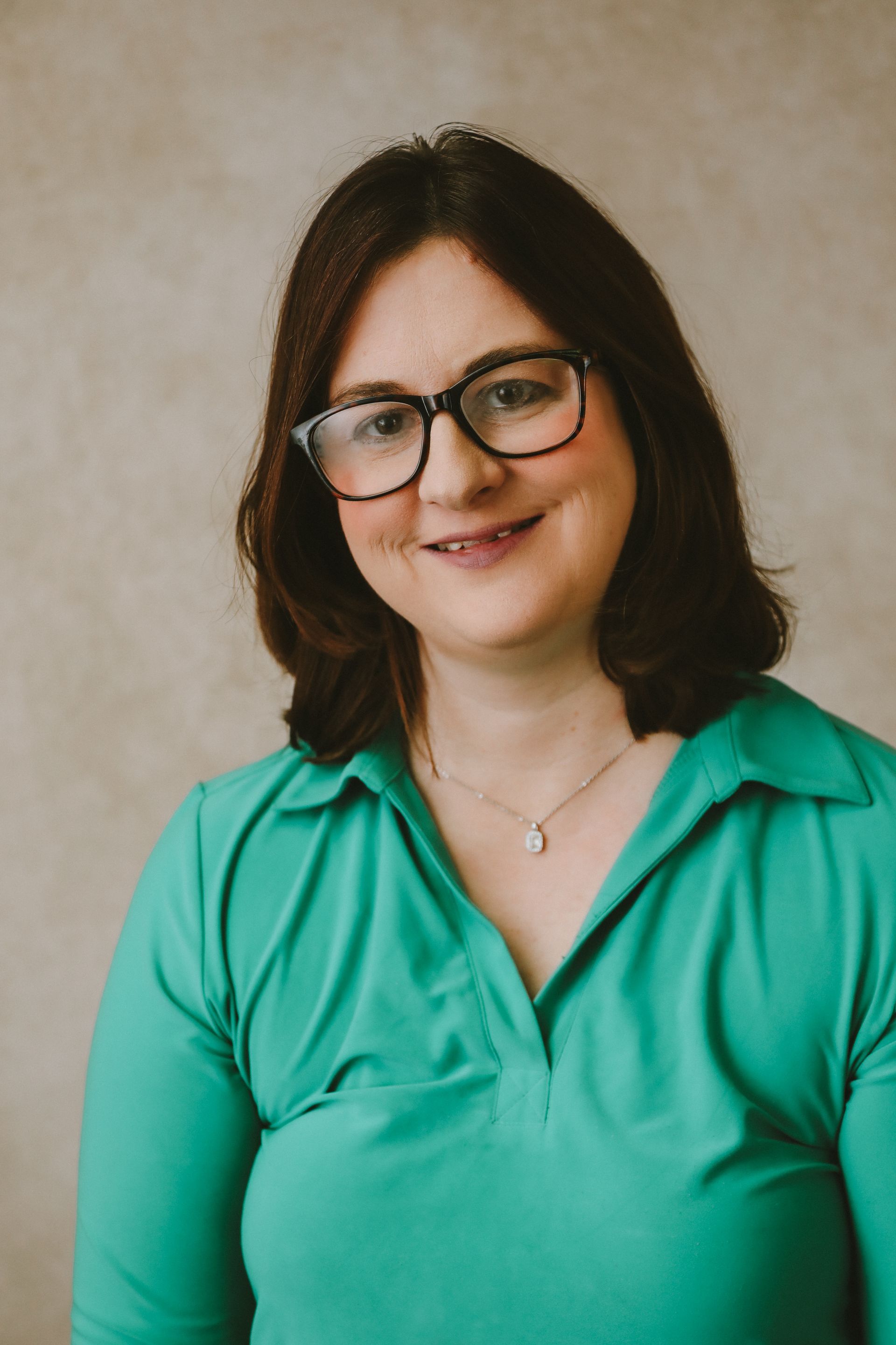 A woman wearing glasses is smiling.