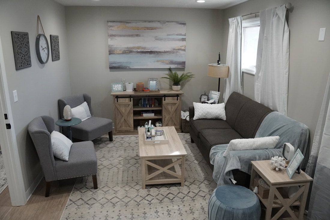 A living room with a couch , chairs , a coffee table and a painting on the wall.