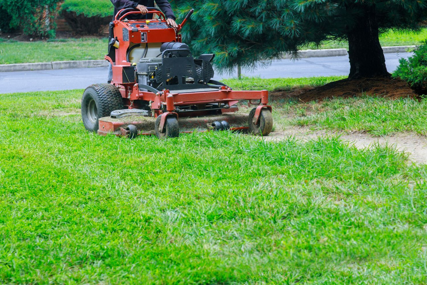 A man is riding a lawn mower on a lush green lawn.