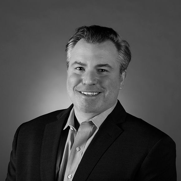 A man in a suit and tie is smiling in a black and white photo.