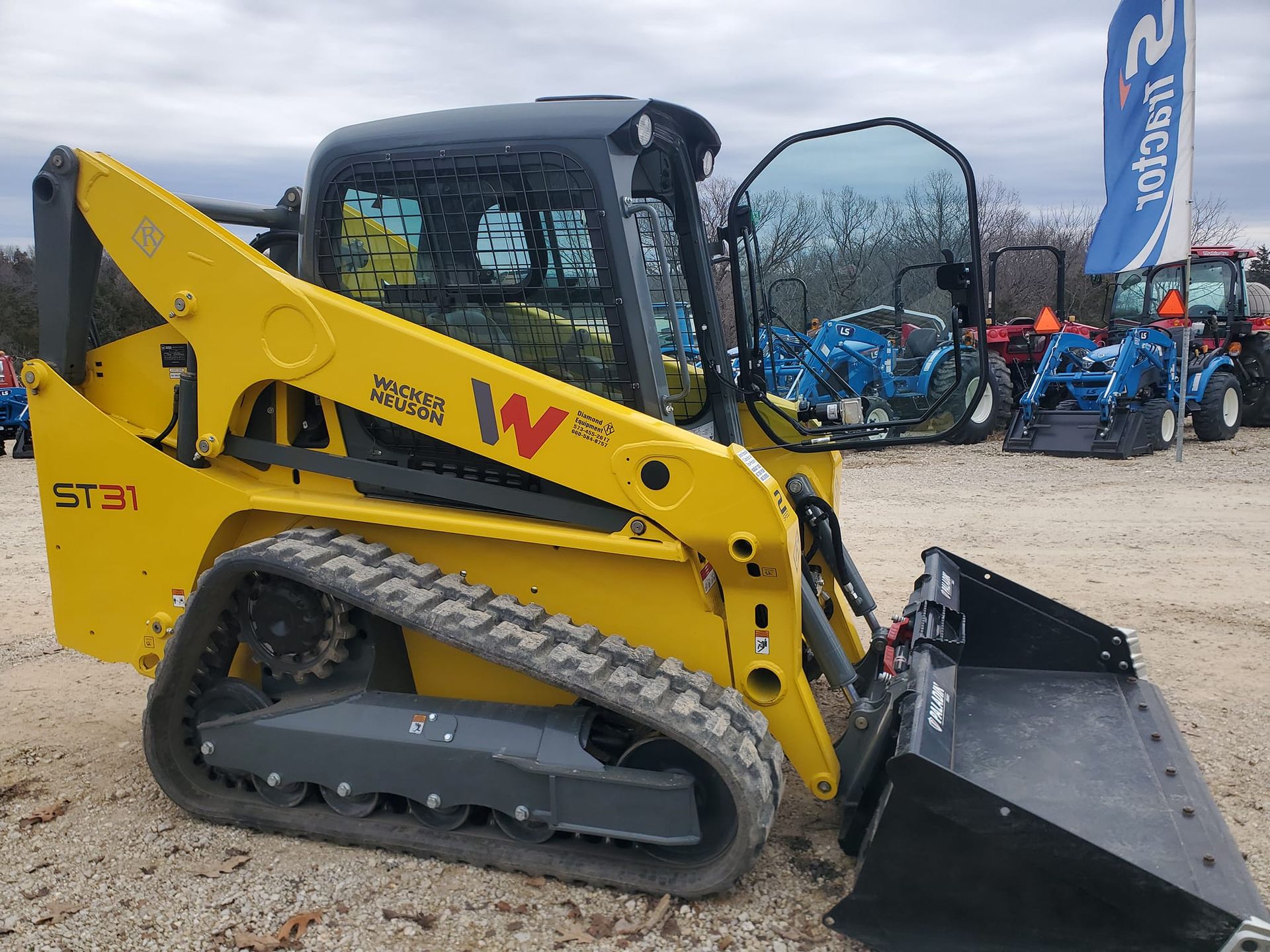 Yellow Wacker Neuson compact track loader with bucket, parked outdoors.