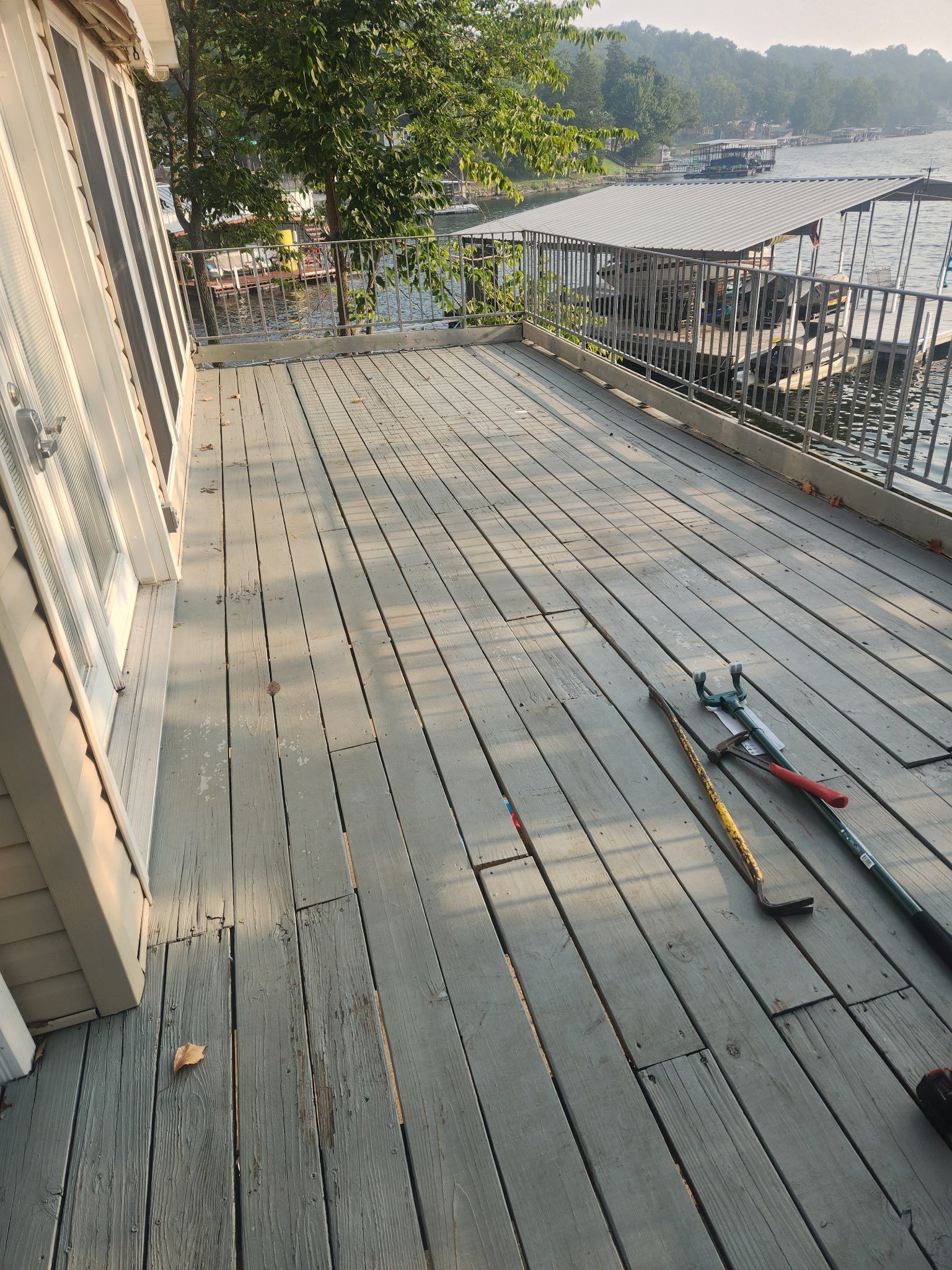 Wooden deck with tools, overlooking water and docks.