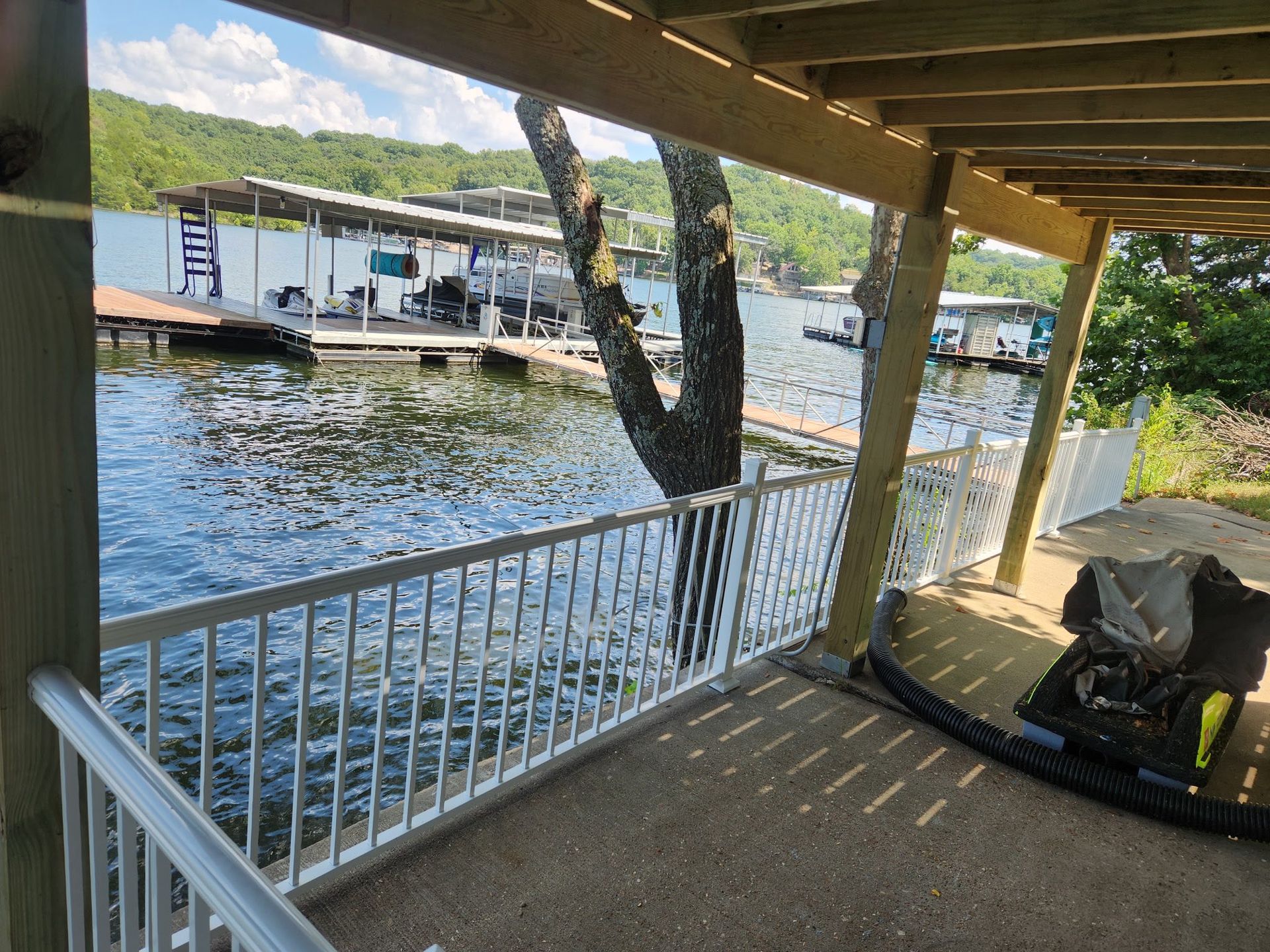 View from a covered patio overlooking a lake with docks and a tree.
