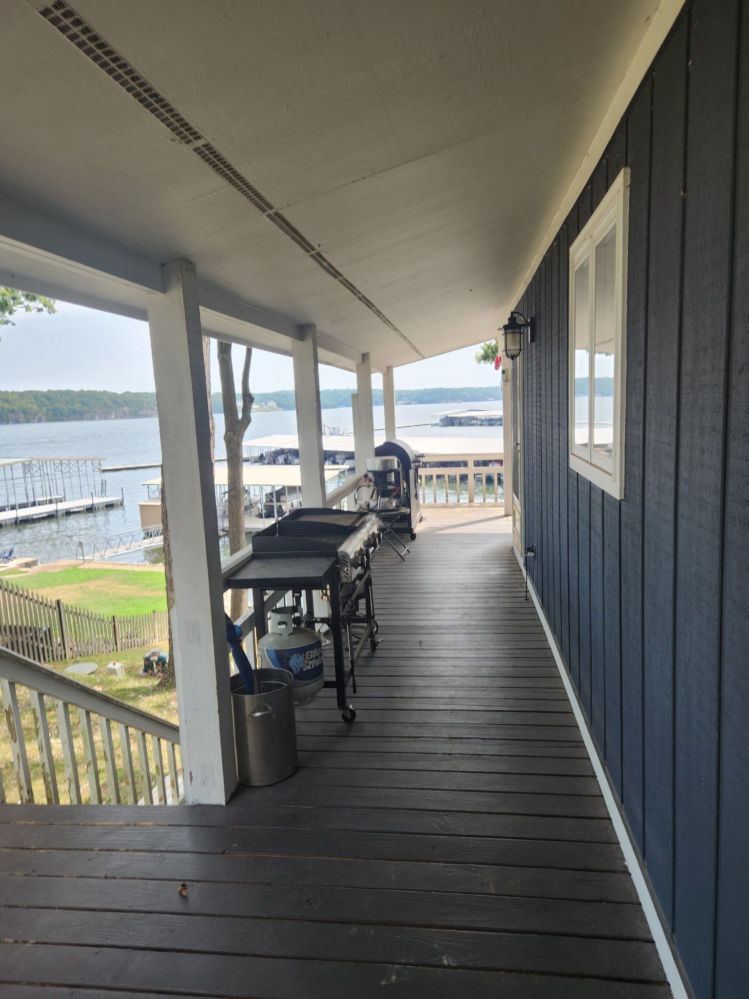 Long porch with blue siding, grills, and a waterfront view.