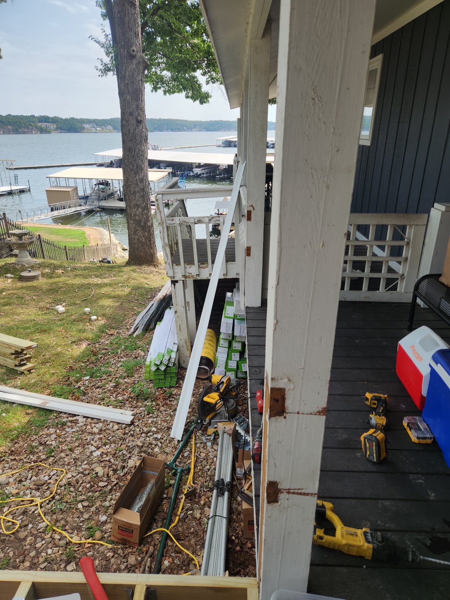 Construction site near a lake. Tools and materials on a porch, dock, and unfinished deck.
