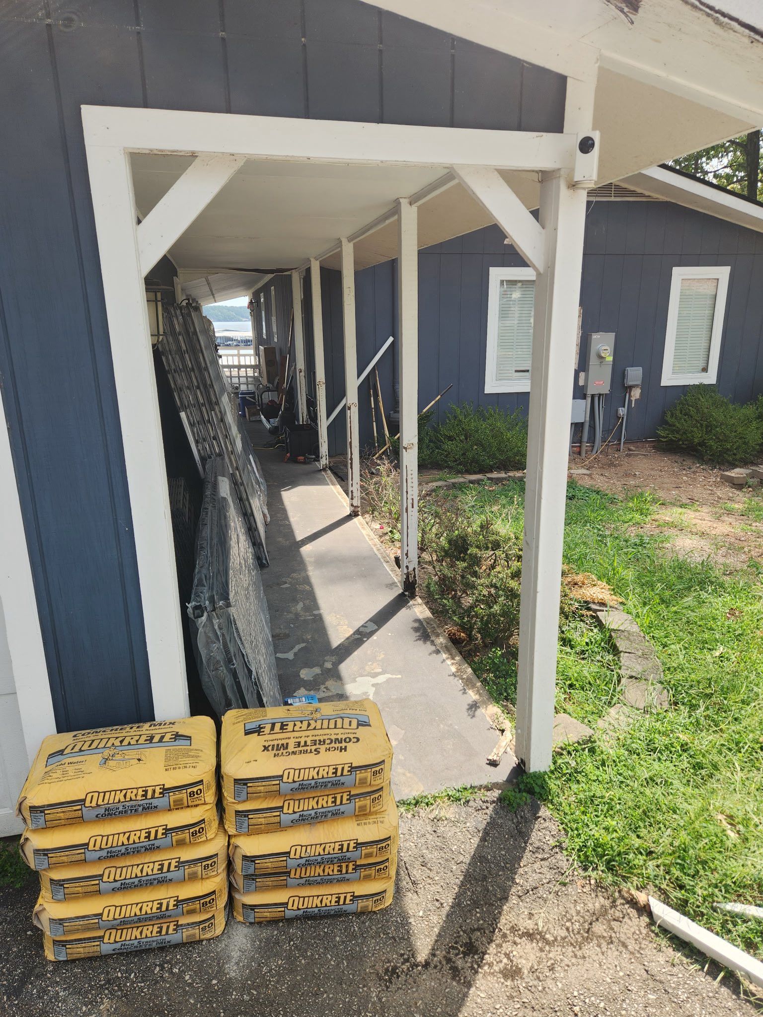 Yellow boxes stacked on a sidewalk under a white-framed porch with blue siding.