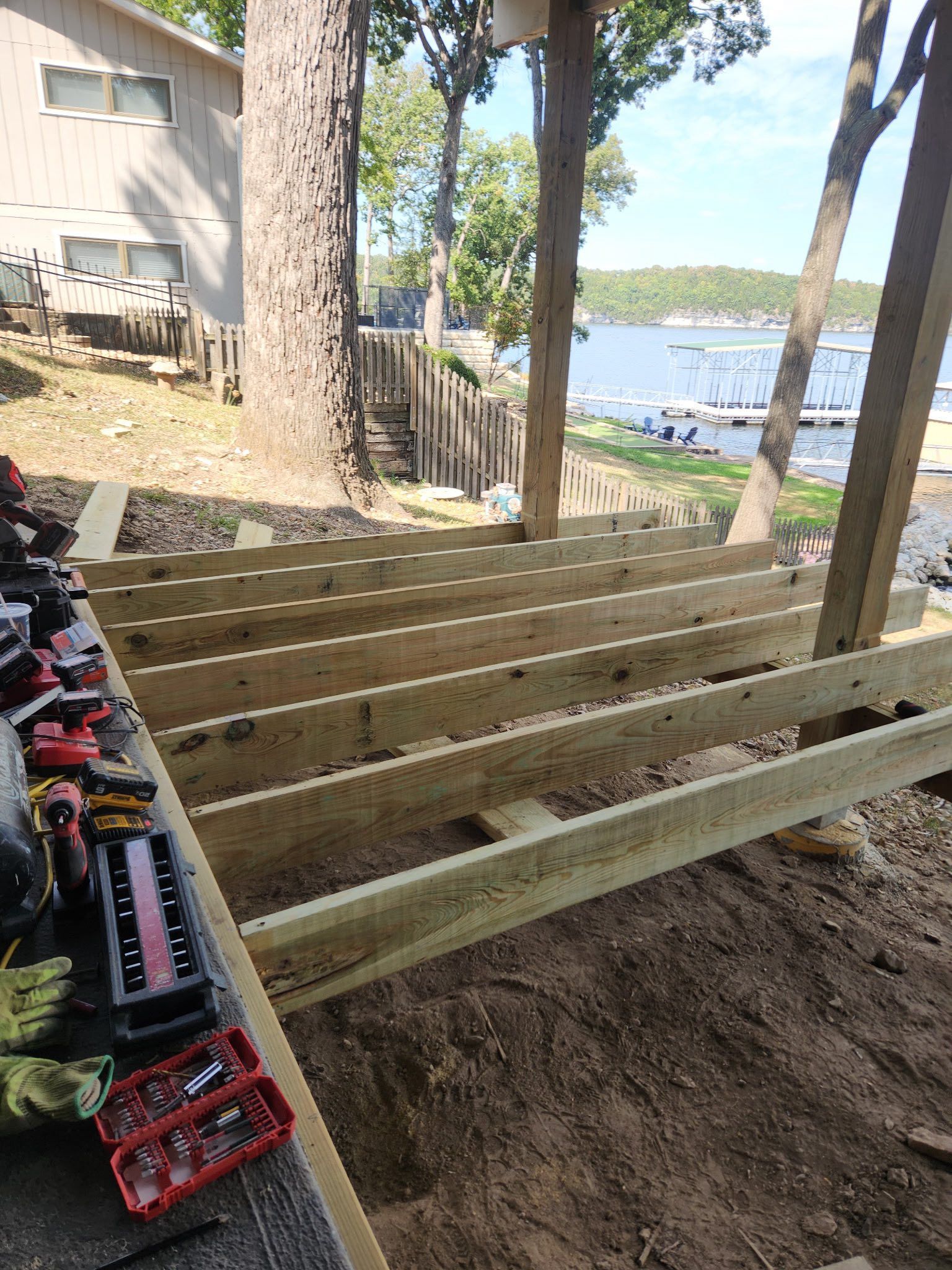 Wooden deck under construction near a lake; tools on deck.